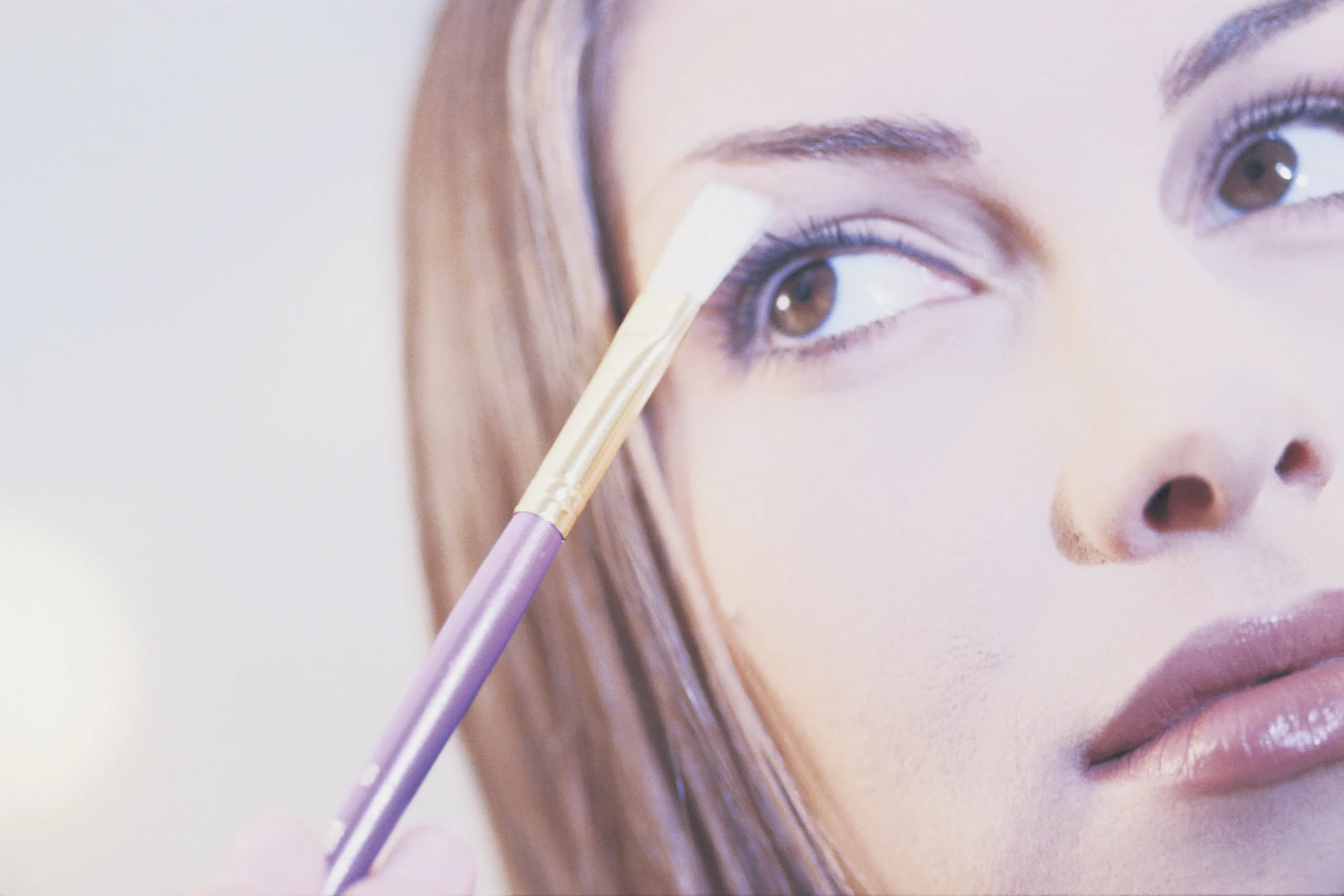 Person applying makeup to their eyebrow using a brush, demonstrating makeup techniques. Makeup Tips and Tricks by yesvsno.