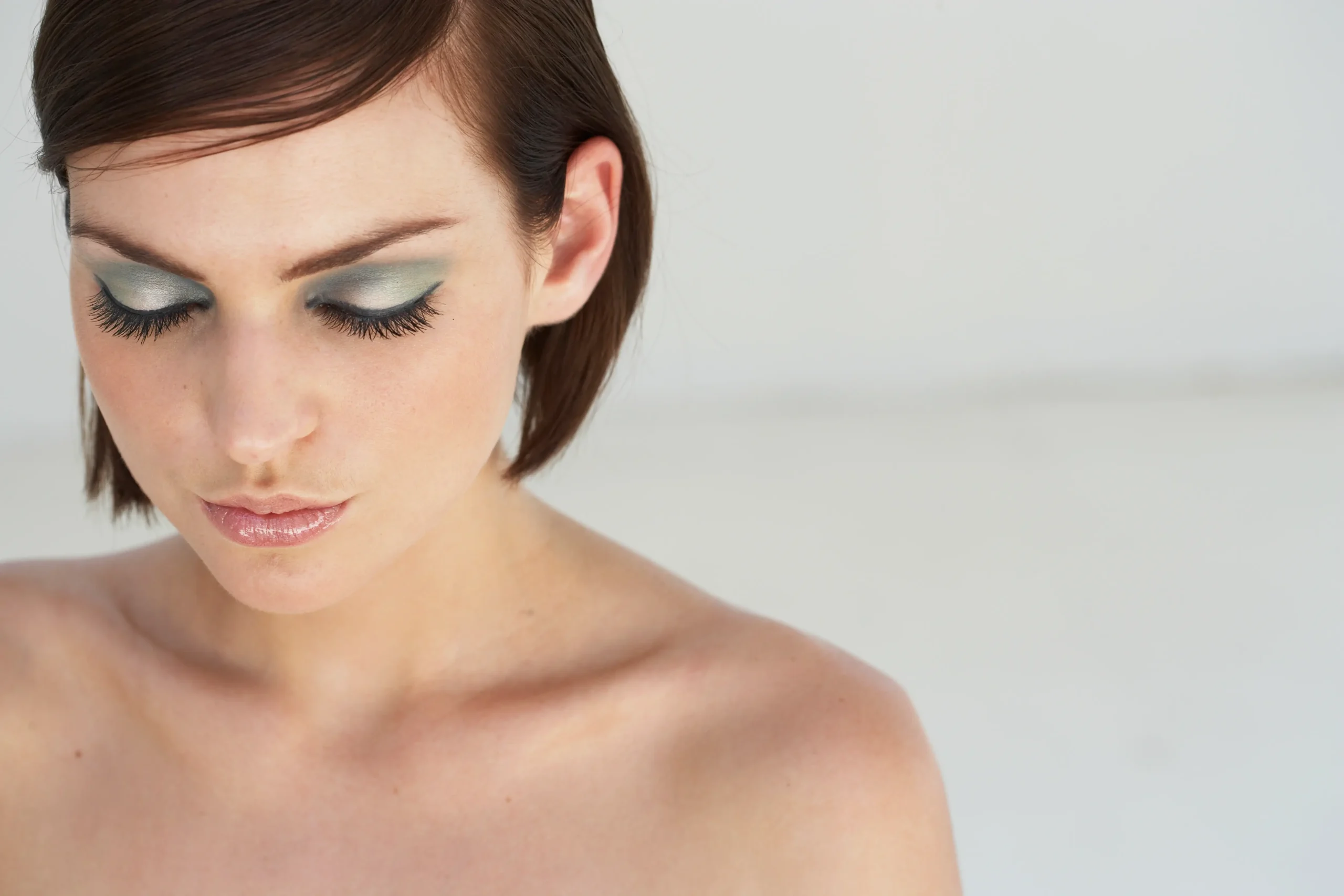 Woman with dramatic eye makeup featuring green eyeshadow and voluminous lashes, demonstrating makeup tips and tricks. Makeup Tips and Tricks by yesvsno