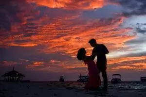 Couple enjoying a romantic moment on the beach during sunset. Perfect idea for a date night. Date night ideas and inspiration at yesvsno.net.