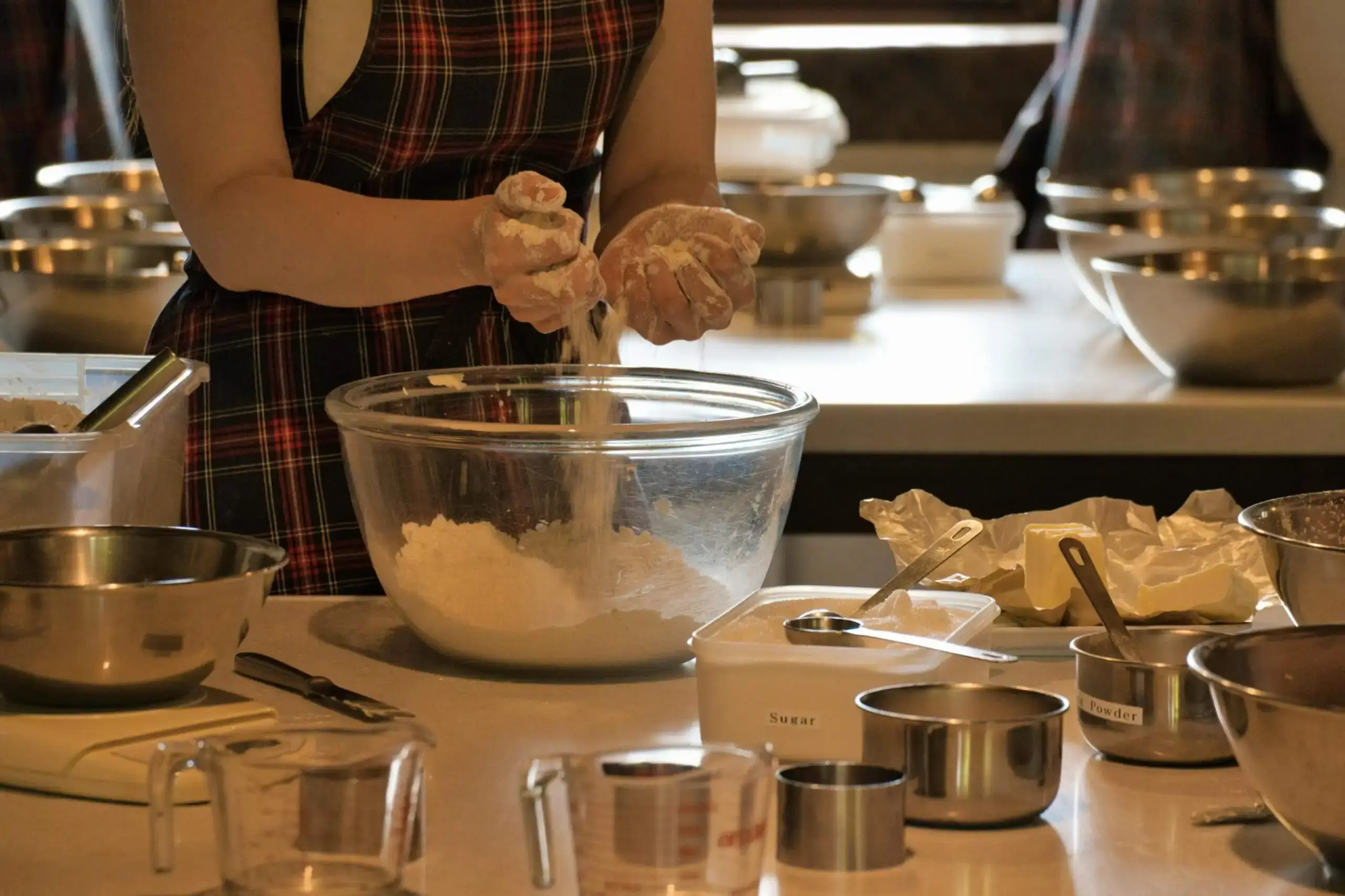Person preparing ingredients in the kitchen, mixing flour in a bowl. Great activity for a cozy date night at home. Explore more date night ideas at yesvsno.net
