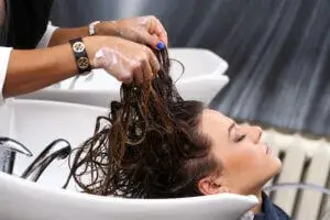 Hair stylist performing a hair wash treatment, applying professional hair care products. Explore the best hair hacks for healthy and shiny hair at YesVsNo.