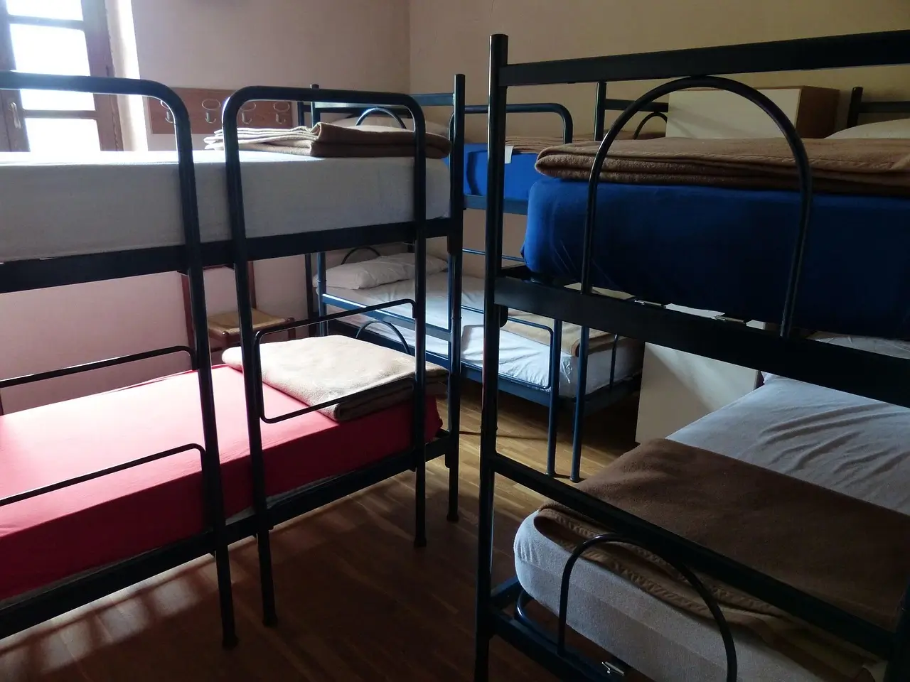 Hostel room with multiple bunk beds, showcasing a budget-friendly option for travelers. Hostel or Airbnb by yesvsno.net.