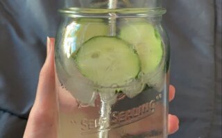 A glass pitcher of fruit and herb infused water with lemon, cucumber, and mint, bright and refreshing kitchen counter setting, no identifiable brand logos.
