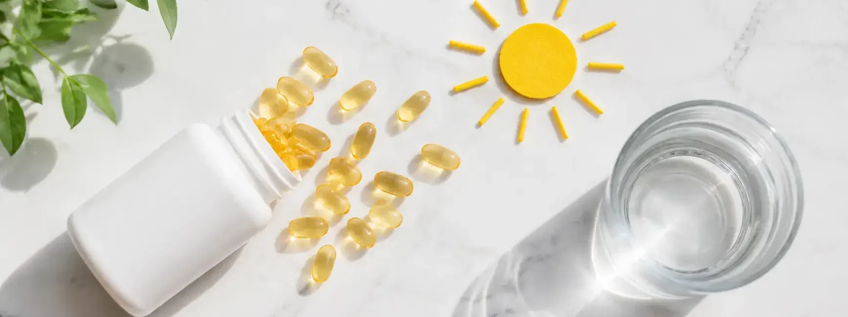 Flat lay of Vitamin D supplement capsules spilling from a white bottle onto a bright marble surface with a glass of water and a sun motif symbolizing sunlight exposure, clean minimal health concept — vitamin D supplement benefits daily use - YesVsNo.net.