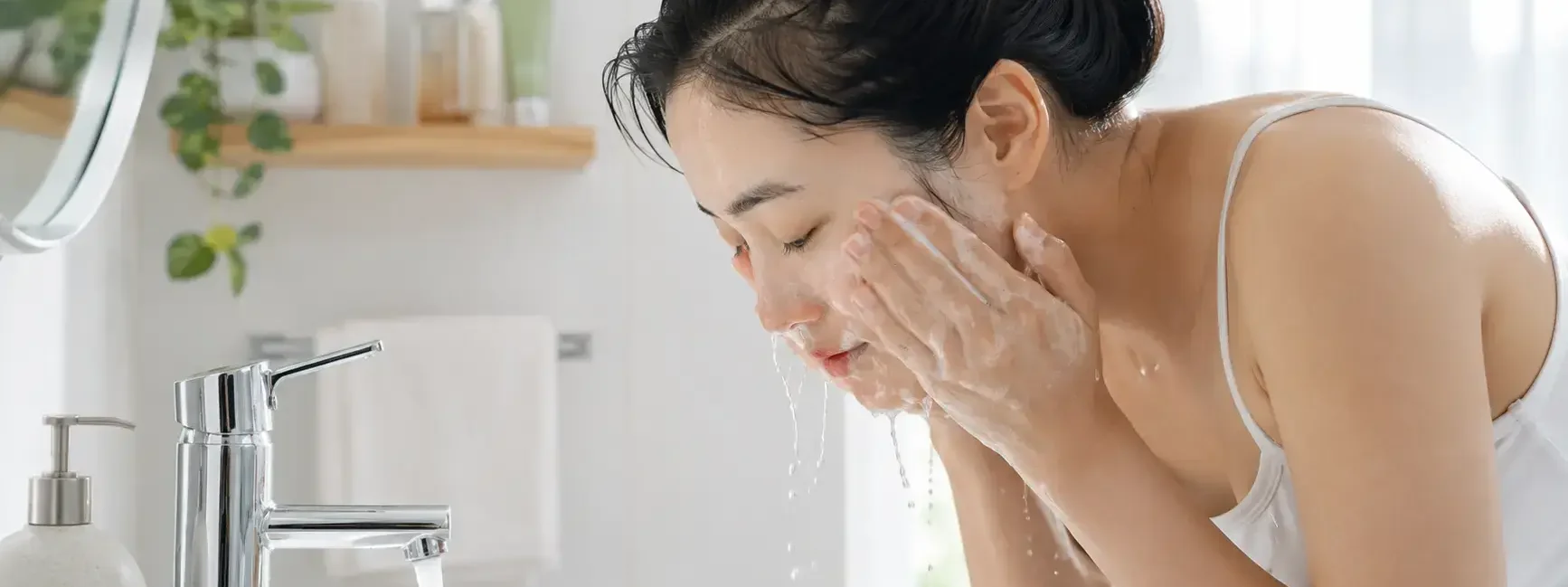 A person with bare, makeup-free skin washing their face with a simple gel cleanser at a bright bathroom sink, natural morning light, minimal product shelf visible.yes or no to double cleansing without makeup featured image.