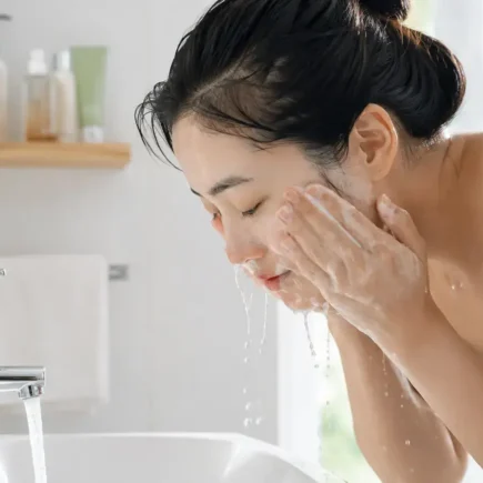 A person with bare, makeup-free skin washing their face with a simple gel cleanser at a bright bathroom sink, natural morning light, minimal product shelf visible.yes or no to double cleansing without makeup featured image.