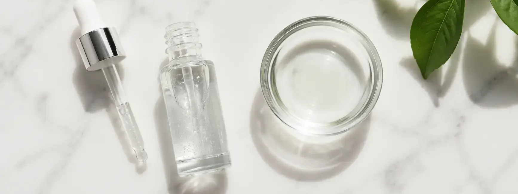 Niacinamide serum bottle with dropper and water bowl on a clean marble surface in minimal skincare style — niacinamide serum for oily skin routine - yes or no to niacinamide for oily skin.
