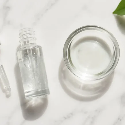Niacinamide serum bottle with dropper and water bowl on a clean marble surface in minimal skincare style — niacinamide serum for oily skin routine - yes or no to niacinamide for oily skin.